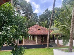 a house with a red roof and some palm trees at RiverSoul Pool Villa in North Paravur