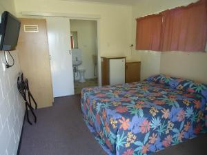 a hotel room with a bed and a bathroom at Moondarra Motel in Innisfail