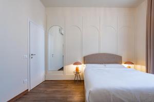 a bedroom with a white bed and a mirror at Lumi Stays in Florence