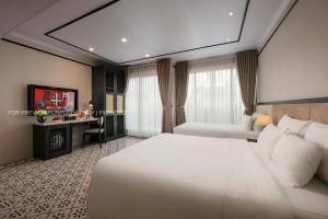 a hotel room with a large white bed and a desk at The Emissary Hanoi Hotel & Spa in Hanoi
