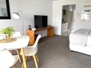 a living room with a table and a tv and a bed at Bay View Ocean Views in Lorne
