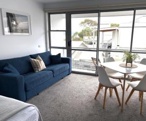 a living room with a blue couch and a table at Bay View Ocean Views in Lorne +1 photo