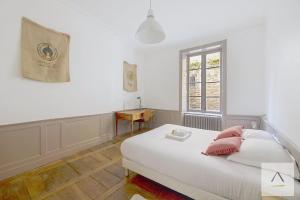 a bedroom with a bed with pink pillows and a window at L'Historique in Rennes