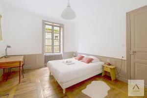 a bedroom with a white bed with pink pillows at L'Historique in Rennes +9 photos