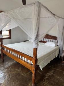 a wooden bed with a canopy in a room at Blue House Watamu in Watamu