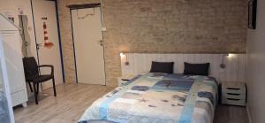 a bedroom with a bed and a brick wall at Au Fil de l'Eau in La Ronde