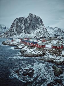 a group of red buildings on a island in the water at 2 Houses & A Barn Double Room in Vestvågøya +20 photos