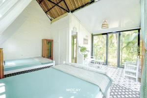 a bedroom with two beds in a room with windows at MOCAY farmstay in Ben Tre