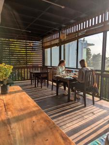 two people sitting at a table on a deck at Cloudy Hill Cottage in Ella