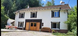 a white house with a wooden door and a table at Le Gîte de Hildegarde in Granges-Aumontzey