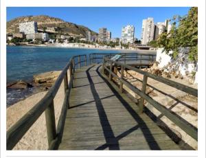 a wooden boardwalk on the beach with a city in the background at Habitación individual en la playa in Alicante +5 photos