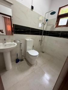 a bathroom with a white toilet and a sink at Southern Hight's Villa in Unawatuna