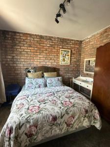 a bedroom with a bed and a brick wall at Your home in the Cape in Cape Town