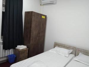 a bedroom with two beds and a wooden cabinet at TOPTEN Hotel Tashkent in Yalanghoch