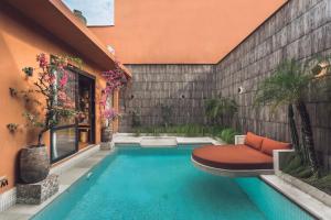 a swimming pool with a bench next to a building at Sana Vie Villa Seminyak by Ini Vie Hospitality in Seminyak