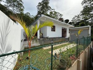 a white house with a fence in front of a yard at Southern Hight's Villa in Unawatuna