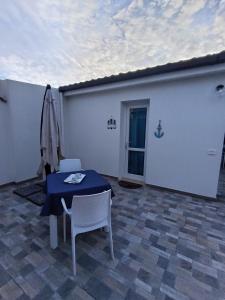 eine Terrasse mit Tisch, Stühlen und Sonnenschirm in der Unterkunft CasAmedeo in Calasetta