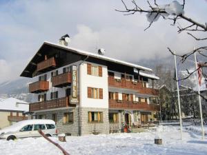 a building in the snow with a car parked in front at Meublè Cima Bianca Garni in Bormio