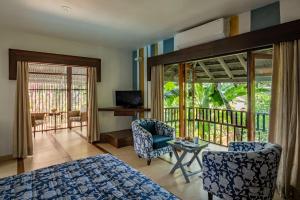 a bedroom with a bed and chairs and a balcony at Casa Vagator in Vagator