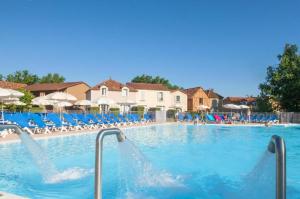 a large swimming pool with blue chairs and umbrellas at Maison 3 chambres - 6-8 personnes - piscine chauffée - jacuzzi - internet - parking - Idéal familles & pros in Monflanquin