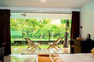two chairs sitting on a deck in a bedroom at Forest Dew Udawalawa in Udawalawe
