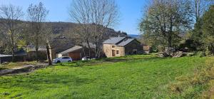 a green field with a house and a car on a hill at Oustal de Piarelle in Saint-Jean-du-Bruel