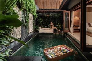a pool in the middle of a house with a woman sitting in a tub at Seminyak Sanctuary Villa by Ini Vie Hospitality in Seminyak