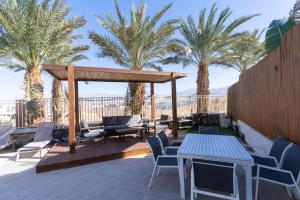 a patio with chairs and a gazebo and palm trees at villalis bay view in Eilat