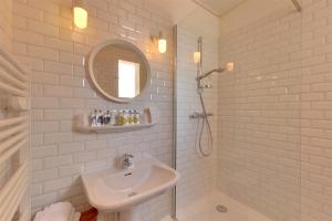 La salle de bains blanche est pourvue d'un lavabo et d'une douche. dans l'établissement Hôtel L'orque Bleue, à Sète