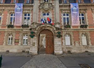 a building with a wooden door and flags on it at Château Walk Studio Appartement in Fontainebleau