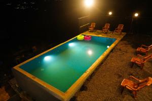 a swimming pool at night with chairs around it at DreamNest Vagamon in Vagamon