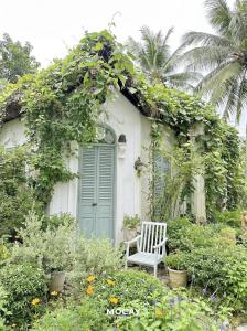 a white house with a green door and a chair at MOCAY farmstay in Ben Tre