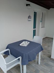 ein Tisch mit einer blauen Tischdecke und zwei Stühlen in der Unterkunft CasAmedeo in Calasetta
