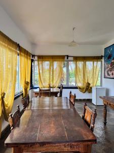 a dining room with a large wooden table and yellow curtains at Blue House Watamu in Watamu