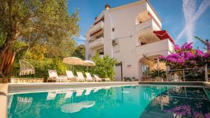 a house with a swimming pool in front of a building at Apartments Padovan in Rab
