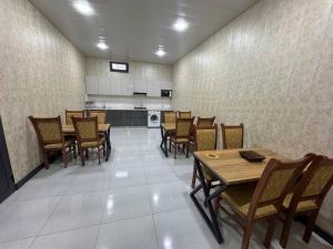 a dining room with tables and chairs and a kitchen at Best Guest House in Andizhan