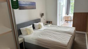 a bedroom with a bed with white sheets and pillows at Hotel Zur schönen Aussicht in Grömitz