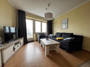 a living room with a black couch and a tv at Hotel Zur schönen Aussicht in Grömitz