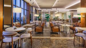 a restaurant with tables and chairs and large windows at فندق ترى النزهة -Tura Hotel AlNuzha in Riyadh