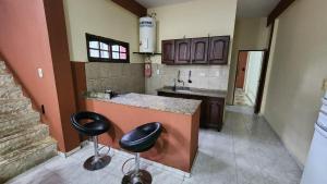a kitchen with two bar stools and a counter at Casa Rivadavia en El Paso in Paso de la Patria