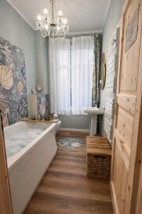 a bathroom with a bath tub and a chandelier at N&N Altbau-Apartments Schwerin nähe Schloss & Zentrum in Schwerin +79 photos