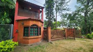 a red house with a gate and a fence at Casa Rivadavia en El Paso in Paso de la Patria