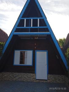a house with a pointed roof with a door at Chalés Caraguatatuba in Caraguatatuba