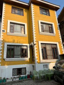 a yellow building with green chairs in front of it at Golden Mud in Srinagar