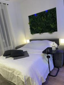 a bedroom with a white bed with a plant on the wall at All in relaxation in Toulouse