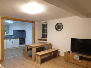 a living room with a table and a clock on the wall at Ferienwohnung zur Honigschleife in Langweiler