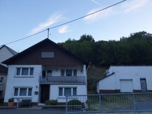 a white house with a porch and a balcony at Ferienwohnung zur Honigschleife in Langweiler