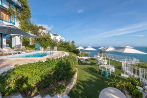 a pool with umbrellas and tables and chairs and the ocean at La Demeure in Sidi Bou Saïd