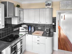 a kitchen with white cabinets and a white refrigerator at 3-Bed Duplex Flat, Free WIFI & Great Transport Links in Norwood