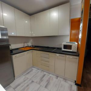 a kitchen with white cabinets and a microwave at Абзал in Karagandy